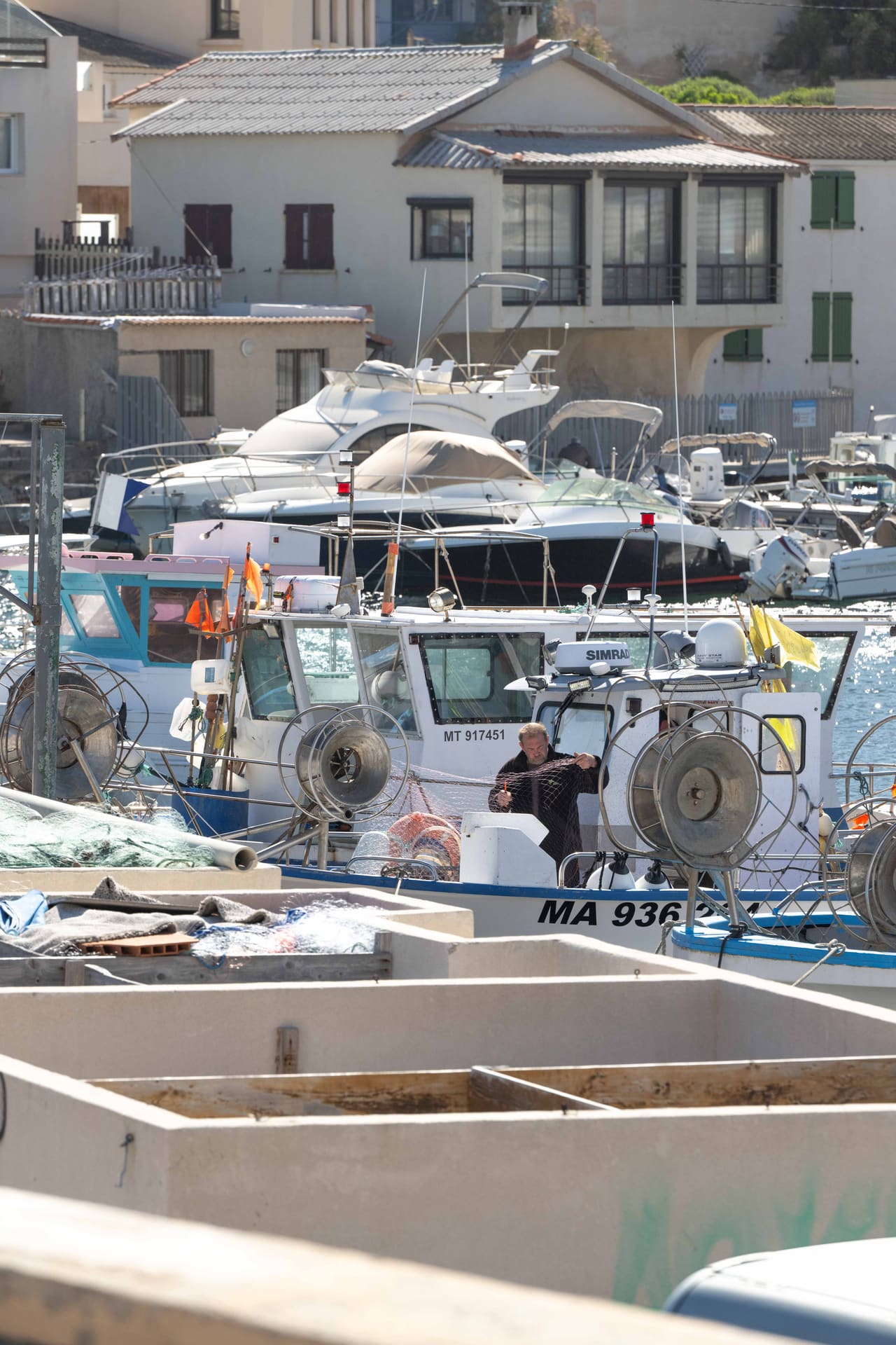 Un pêcheur démaille ses filets sur son bateau, au port des Goudes